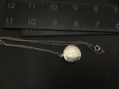 Sale Photo Thumbnail #51: A vintage oval locket pendant necklace featuring an etched floral motif on the front cover. The locket opens to reveal space for two small photos. Comes attached to a fine chain with a spring ring clasp. Shows light tarnishing and wear consistent with age