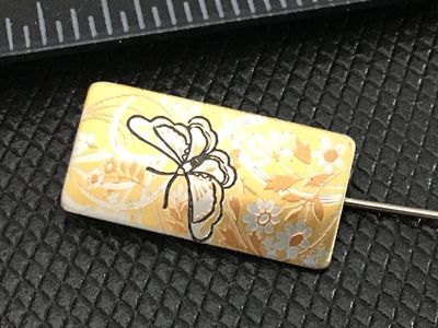 Sale Photo Thumbnail #195: A vintage Reed & Barton Damascene rectangular stick pin featuring a butterfly and floral motif in gold, silver, and black tones on a yellow background. Marked 'Reed & Barton Damascene' on the reverse. Measures approximately 2 inches in total length includ