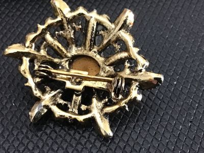 Sale Photo Thumbnail #210: Vintage gold-tone ornate filigree brooch featuring a central oval pink cabochon accented by faux pearls and turquoise-color beads. Features a safety pin clasp closure on the back. Shows light surface wear and finish aged patina consistent with age. Measur