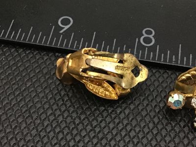 Sale Photo Thumbnail #85: Pair of vintage gold-tone floral clip-on earrings featuring leaves, faux pearl flower centers, and rhinestone accents, including aurora borealis stones. Marked AUSTRIA on the clips. Measure approximately 1 inch in length. Exhibits light vintage wear and p