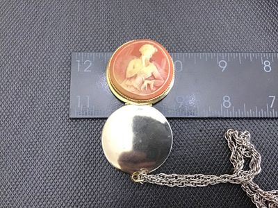 Sale Photo Thumbnail #43: Vintage costume jewelry necklace featuring a round hinged locket with a faux cameo motif depicting a classic female profile against a peachy-pink background set in a gold-tone beaded bezel. Attached to a silver-tone/gold-tone chain. The pendant measures a