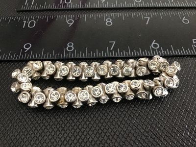 Sale Photo Thumbnail #235: A vintage silver-tone stretch bracelet featuring bezel-set clear rhinestones in flared, hourglass-shaped metal links. Measures approximately 5 inches unstretched. Shows light vintage wear and tarnish to the silver-tone finish; all stones appear present.