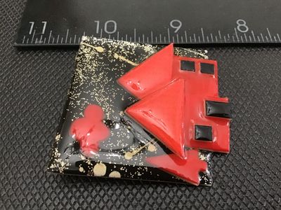 Sale Photo Thumbnail #73: A vintage artisan brooch labeled 'House Pins by Lucinda', Portland, ME. Features a colorful red house scene against a black background with gold glitter accents. Crafted with resin/plastic materials and a rollover safety clasp on the reverse. Measures app