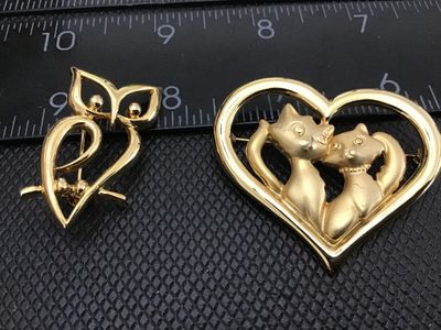 Sale Photo Thumbnail #79: Pair of vintage gold-tone animal brooches/pins. Includes an openwork stylized owl brooch and a Jonette Jewelry (JJ) brooch featuring two cats inside a heart frame. Both pieces have standard rollover safety pin clasps on the back. Show light vintage wear w