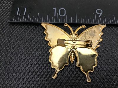 Sale Photo Thumbnail #70: Gold-tone butterfly brooch featuring vibrant purple, pink, and iridescent glitter enamel details. Measures approximately 2 inches in width. Standard pin back mechanism. Shows minor vintage wear on the back side, otherwise in good pre-owned condition.