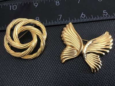 Sale Photo Thumbnail #160: Pair of vintage gold-tone brooches featuring a textured swirl knot brooch signed Monet and a ribbed butterfly brooch. Both pieces feature secure pin backs and classic mid-to-late 20th century styling. In very good vintage condition with bright gold-tone f