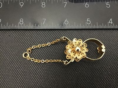 Sale Photo Thumbnail #48: Vintage gold-tone metal glove clip featuring a delicate filigree flower center design, textured metal band clip, and an attached safety chain with spring ring clasp. Decorative antique/vintage fashion accessory. Measures approximately 3 to 4 inches in len