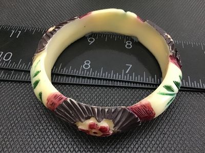 Sale Photo Thumbnail #61: Vintage carved Celluloid bangle bracelet featuring painted floral and fan details in red, green, brown, and cream tones. Measures approximately 3 inches in outer diameter. Shows minor surface wear consistent with age.