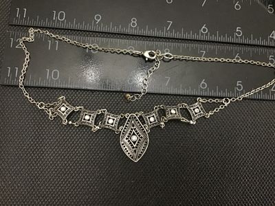 Sale Photo Thumbnail #88: Silver-tone costume jewelry statement necklace featuring openwork geometric/filigree links set with clear rhinestones and a central teardrop-shaped pendant link. Features a lobster claw clasp with an adjustable extender chain. Total chain length is approx