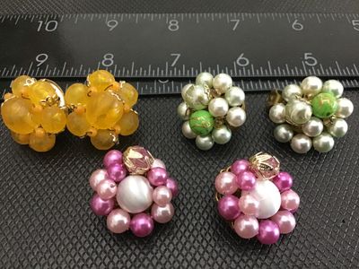 Sale Photo Thumbnail #28: Collection of three pairs of vintage beaded cluster clip-on earrings. Includes one yellow/amber-toned beaded cluster pair, one pink and white faux-pearl cluster pair with filigree detail backing, and one green and faux-pearl cluster pair. Marked 'JAPAN' o