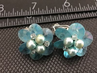 Sale Photo Thumbnail #26: Pair of vintage floral-form clip-on earrings featuring iridescent light blue petals, faux pearl clusters, and small spacer beads. Silver-tone clip backs are marked "JAPAN". Measure approximately 1 inch in diameter. Good vintage condition with light age-ap
