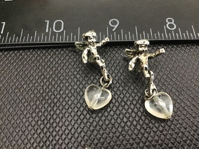 Sale Photo Thumbnail #7: Pair of detailed cherub/angel stud earrings featuring dangling clear glass or quartz heart charms. Measures approximately 1 inch in total length. Silver-tone metal shows light vintage patina, good pre-owned condition with post backs.