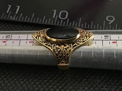 Sale Photo Thumbnail #224: Vintage statement ring featuring an oval black onyx-style cabochon set in an ornate gold-tone filigree frame. The band is stamped "18KT H.G.P." (18K Heavy Gold Electroplate). 

- Ring Size: Approximately size 5 (as measured on mandrel)
- Era/Style: Vintag