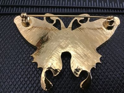 Sale Photo Thumbnail #35: Gold-tone butterfly brooch featuring multi-color pearlescent enamel wings in shades of pink and grey, accented with a purple/iridescent faux opal cabochon center. Pin back clasp is intact and functions properly. Measures approximately 2.5 inches wide. Goo