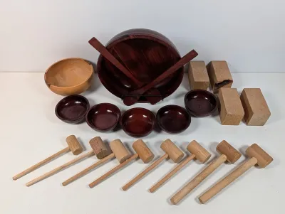 Sale Photo Thumbnail #130: Collection of turned wooden tableware and tools, including a dark mahogany-finish salad bowl set with matching servers and individual bowls, a natural wood bowl, blocks, and several wooden mallets.