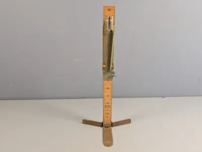 Sale Photo Thumbnail #307: Vintage Pin-It skirt marker featuring a wooden ruler with printed inch increments mounted on a metal folding base, including an adjustable chalk applicator slider.