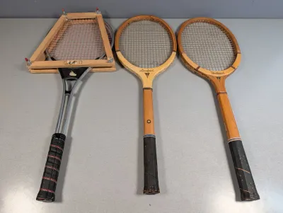 Sale Photo Thumbnail #50: Set of three vintage tennis racquets, including two wooden frames and one metal Crown racquet with a wooden press stretcher.