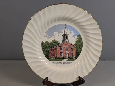 Sale Photo Thumbnail #241: Vintage commemorative ceramic plate featuring an illustration of Salem Walmers Union Church in Indiantown Gap, Pennsylvania, with a spiral swirl border and gold trim.