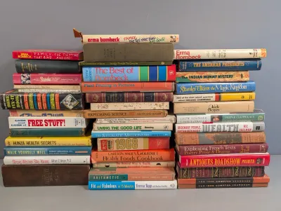 Sale Photo Thumbnail #263: Large assortment of vintage and modern hardcover and paperback books organized in three stacks, covering topics like humor, gardening, health, history, and reference.