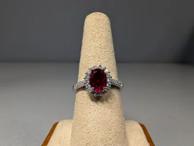 Sale Photo Thumbnail #8: White gold or platinum ring featuring a center oval-cut ruby surrounded by a diamond halo and pavé band.