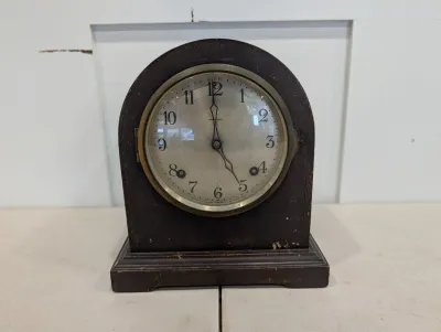 Sale Photo Thumbnail #483: Antique Ansonia arched wooden mantel clock featuring a round dial behind glass bezel, showing light finish wear.