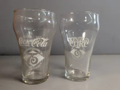 Sale Photo Thumbnail #374: Pair of vintage Coca-Cola 75th Anniversary commemorative glass tumblers featuring printed white graphics, circa 1976.