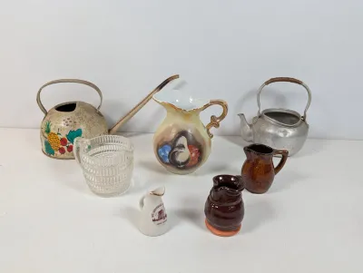 Sale Photo Thumbnail #112: Collection of vintage pitchers, kettles, and creamers, including hand-painted porcelain, ribbed glass, glazed ceramic, metal watering pot, and a aluminum kettle.