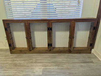 Sale Photo Thumbnail #126: Rustic low wooden display cabinet featuring four glass-panel door frames, black metal hinges, and simple wood knobs.