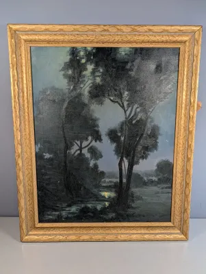 Sale Photo Thumbnail #464: Framed tonalist landscape print depicting a moonlit forest scene with a stream, housed in a carved gilt wood frame.