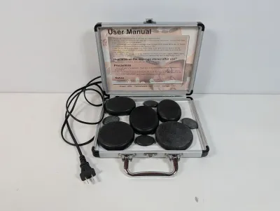 Sale Photo Thumbnail #94: Electric hot stone massage heater kit housed in a silver-tone briefcase with various basalt stones and user manual instructions.