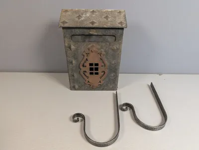 Sale Photo Thumbnail #43: Vintage metal wall-mount mailbox with decorative copper-toned escutcheon plate and two scroll-style newspaper hooks.
