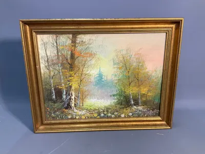 Sale Photo Thumbnail #150: Framed oil painting depicting a forest landscape scene with birch trees and autumn foliage, housed in a molded gilt wood frame.