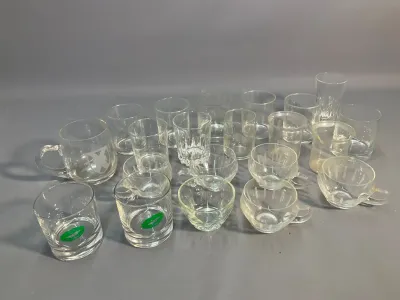 Sale Photo Thumbnail #64: Collection of assorted clear glassware, including novelty green lip tumblers, teacups with handles, and small cut-glass drinking glasses.
