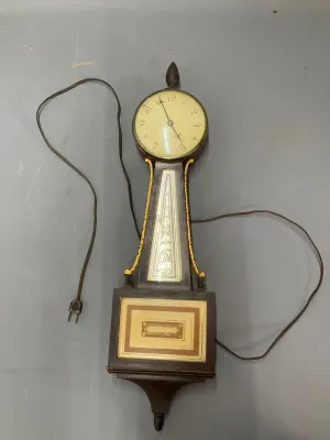 Sale Photo Thumbnail #336: Vintage electric banjo-style wall clock featuring a dark wood case with gilt accents and decorative painted glass panels.