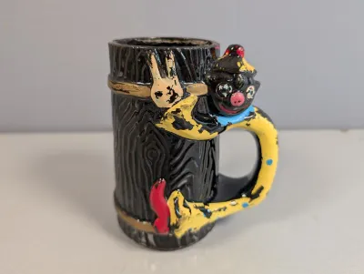 Sale Photo Thumbnail #188: Vintage ceramic novelty mug featuring a hand-painted clown figure attached to a faux wood grain stump, displaying noticeable paint loss and wear.