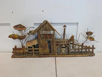 Sale Photo Thumbnail #480: Mid-century brutalist welded copper and brass wall sculpture depicting a blacksmith shop scene with trees, fence, and wagon.