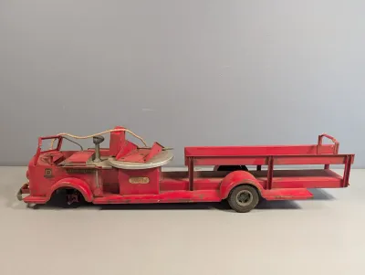 Sale Photo Thumbnail #377: Vintage Doepke Model Toys Rossmoyne pressed steel ladder fire truck missing front wheel and ladder assembly, showing significant play wear and patina.
