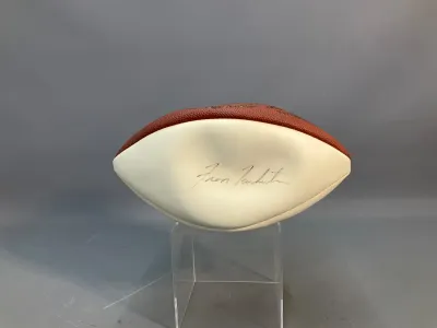 Sale Photo Thumbnail #71: Autographed football featuring a signature on the white panel, mounted on a clear acrylic display stand.