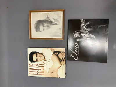 Sale Photo Thumbnail #328: Collection of Elvis Presley memorabilia including a framed black-and-white portrait, an 'Unseen Archives' hardcover book, and a 'Wertheimer Collection' calendar book.