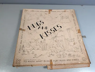 Sale Photo Thumbnail #300: Vintage 1949 "Hugs and Kisses" board game by Edward T. White, featuring whimsical illustrated cover art, showing heavy wear and tape repairs along the edges.