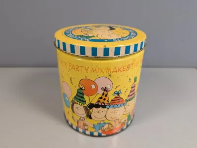 Sale Photo Thumbnail #203: Vintage Peanuts and Chex Party Mix promotional tin canister featuring Charlie Brown, Lucy, and friends, showing light wear and scuffing consistent with age.