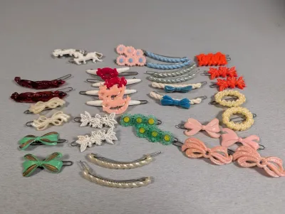 Sale Photo Thumbnail #415: Collection of vintage plastic bobby pins and hair clips featuring various shapes, colors, and motifs including bows, flowers, and horses.