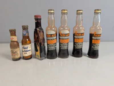 Sale Photo Thumbnail #233: Collection of seven vintage miniature glass bottles, including four Redi-Aid beverage base bottles, miniature Blatz and Pabst Blue Ribbon beer bottles, and an extract bottle.