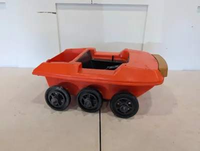 Sale Photo Thumbnail #496: Vintage orange plastic six-wheeled amphibious ATV toy vehicle, showing play wear and missing original windshield and accessories.