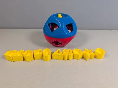 Sale Photo Thumbnail #376: Vintage Tupperware Shape-O toy sorter ball in blue and red plastic, complete with ten yellow shape pieces.