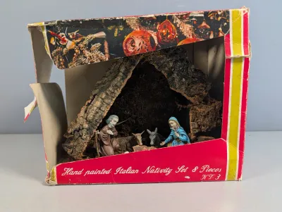 Sale Photo Thumbnail #212: Vintage hand-painted Italian nativity set inside a bark-textured stable, displayed in its original worn packaging.