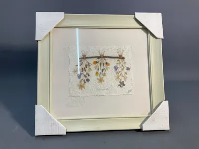 Sale Photo Thumbnail #163: Framed botanical pressed flower artwork titled "Florascapes III", mounted on textured handmade paper inside a light cream frame.