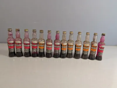 Sale Photo Thumbnail #320: Collection of 13 vintage Redi-Aid beverage base syrup bottles with original printed labels and screw caps.