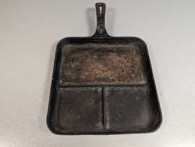 Sale Photo Thumbnail #201: Vintage cast iron divided skillet or breakfast griddle with three cooking compartments, showing signs of wear and surface rust.