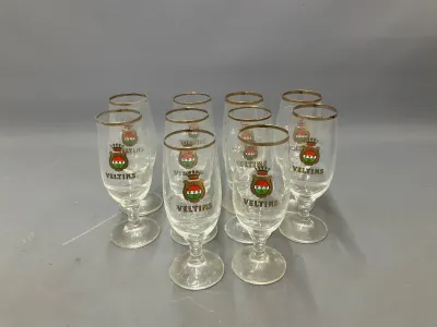 Sale Photo Thumbnail #49: Set of eight vintage Veltins German beer tulip glasses with gold rims and printed crest logos.